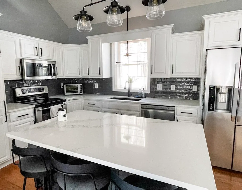 White kitchen with a large quartz island and pendant lights